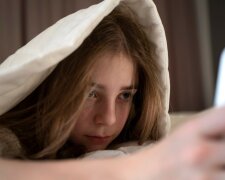 Девушка лежит в кровати с телефоном / фото: Freepik